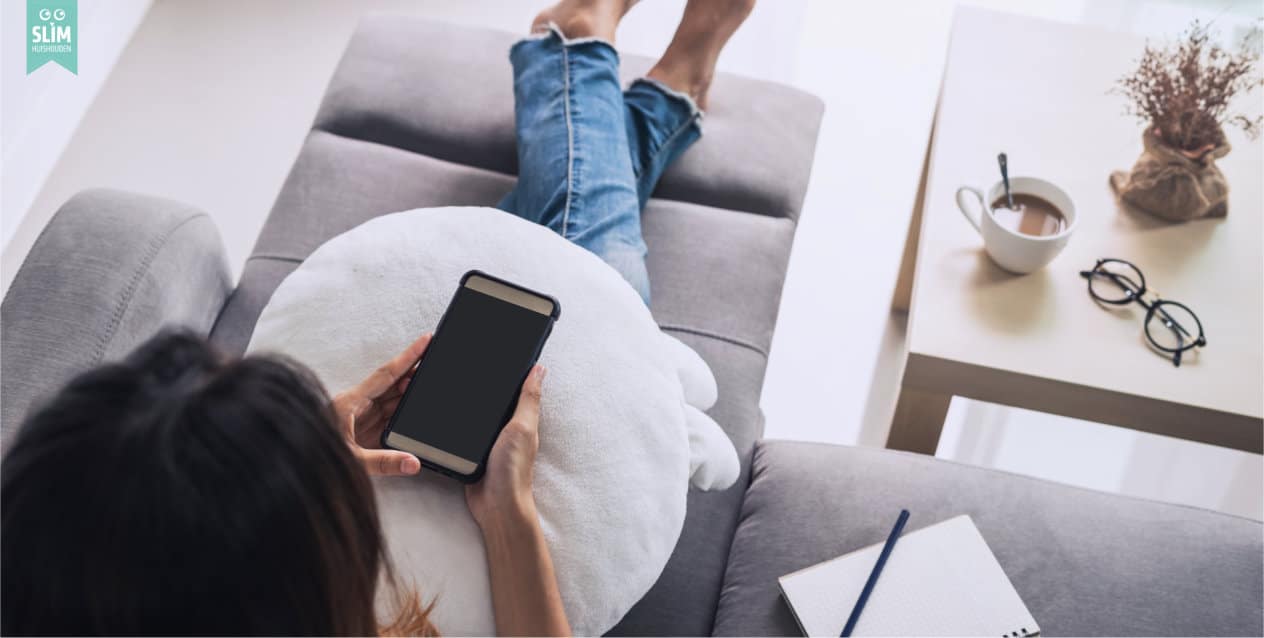 Vrouw zit op bank met telefoon 2024 123RF 107714292