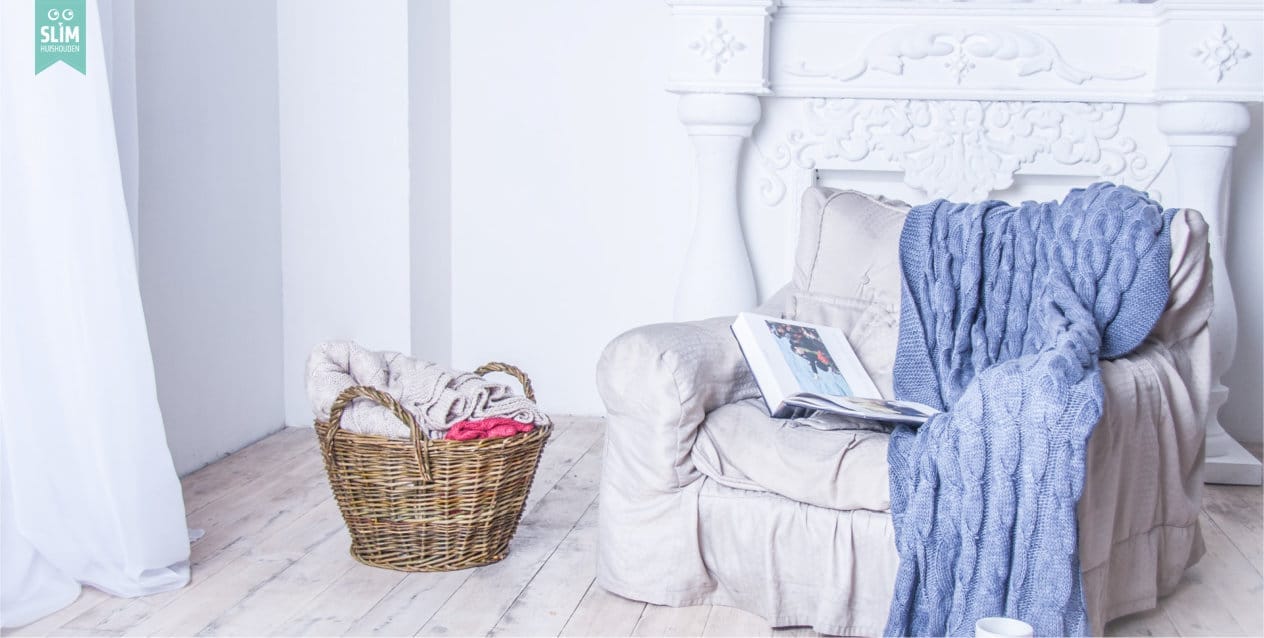 Pag Huishouden Lichtgrijze fauteuil met blauw paars plaid 2024 Shutterstock 77884315 Rustige, opgeruimde woonkamer die ruimte en ontspanning uitstraalt – Slim Huishouden