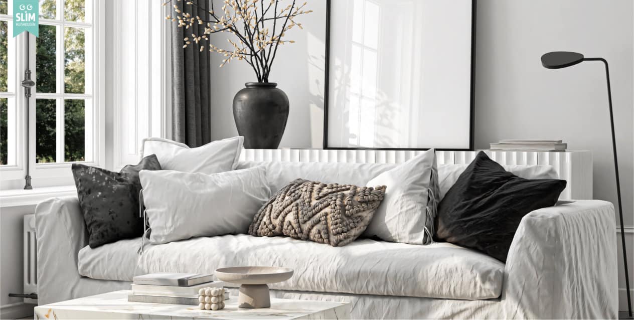 Lichte moderne woonkamer met bank en kussens, planten en een salontafel