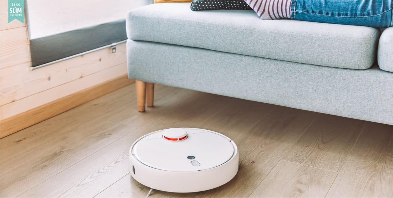 Robotstofzuiger rijdt onder een bank terwijl een klein deel van de benen van een persoon op de bank zichtbaar zijn