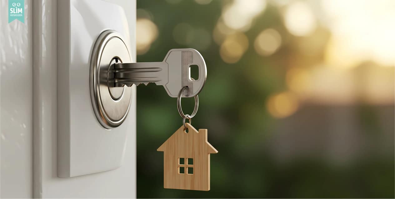 Sleutel in het slot van een voordeur met sleutelhanger in de vorm van een huis