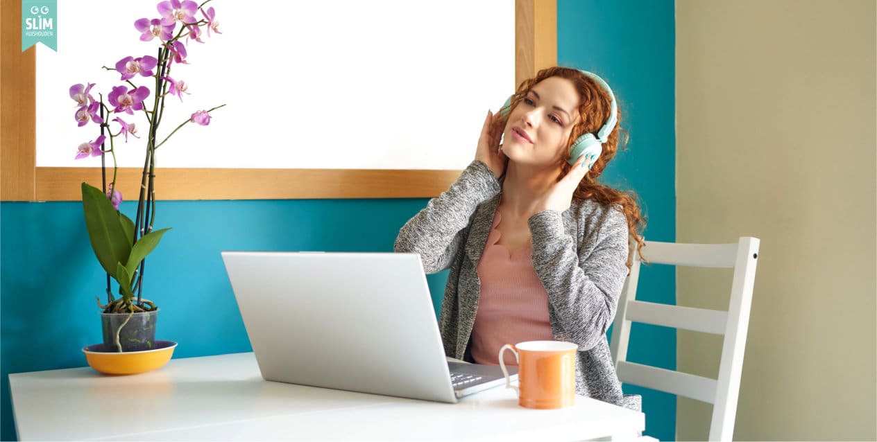 Blog Vrouw met koptelefoon werkt rustig aan laptop met kop thee Vrouw met koptelefoon werkt rustig aan laptop met kop thee