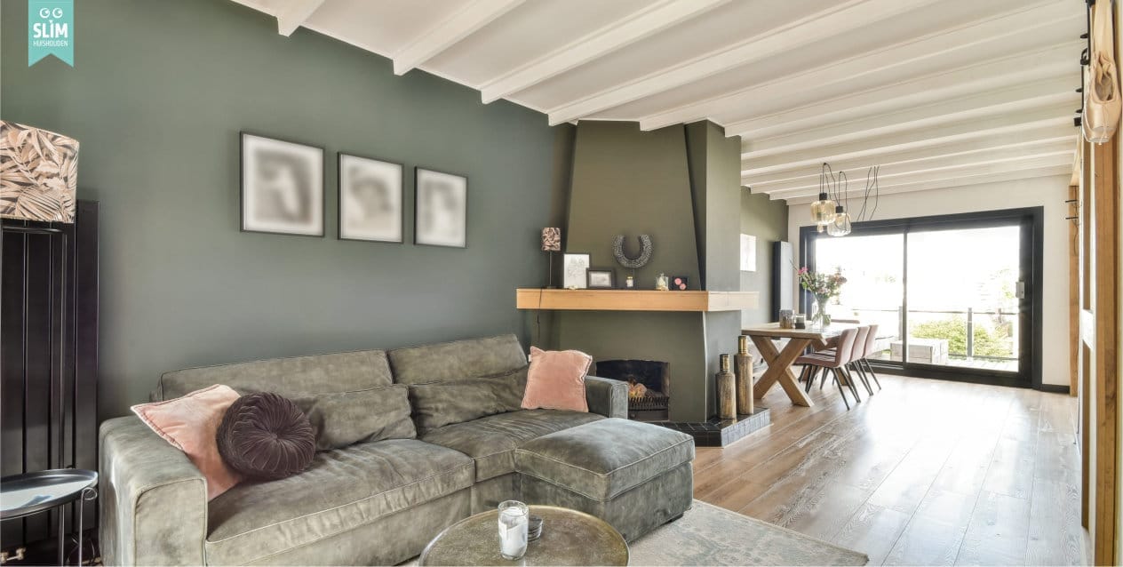 Woonkamer met grijsgroene muur, neutrale kleuren en multifunctionele inrichting met bank en eethoek 